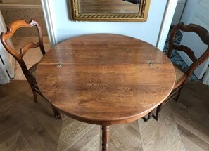 Ein runder Holztisch mit vier Stühlen, ein Spiegel an der Wand und ein strukturierter Boden.