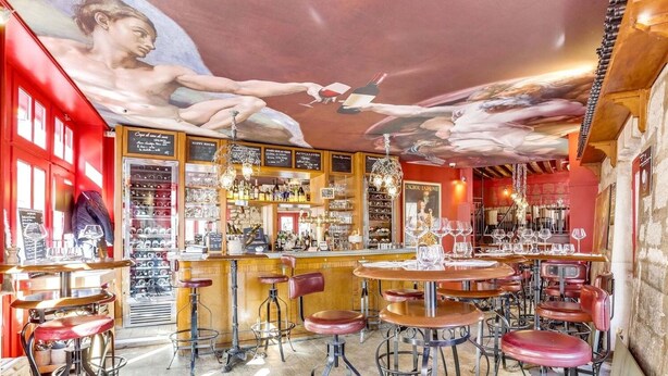 A bar with multiple stools and a mural on the wall.
