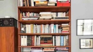 A bookshelf filled with books, a lamp, and a framed picture on the wall.