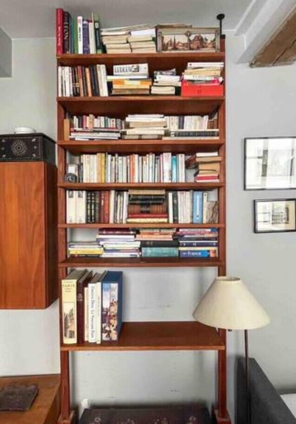 A bookshelf filled with books, a lamp, and a framed picture on the wall.