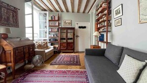 A cozy living room with a sofa, a wooden cabinet, a bookshelf, and a patterned rug.
