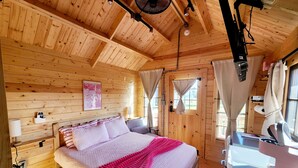 Een houten slaapkamer met een bed, nachtkastje en een raam met gordijnen.