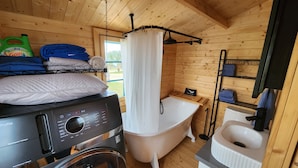 Une petite salle de bain équipée d’un lave-linge, d’une baignoire et de toilettes.