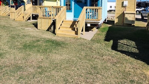 Une rangée de petites cabanes colorées, dotées de terrasses en bois et d’escaliers menant à l’entrée.