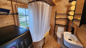 Un bagno piccolo con finiture in legno, una lavatrice nera, un water e un lavandino.