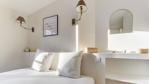 A modern bedroom with a large bed, two wall-mounted lamps, a framed inspirational quote, a mirror, and a small shelf with baskets. - The Sparkle - Tour Eifflel view by Mon Petit Faré (Paris)