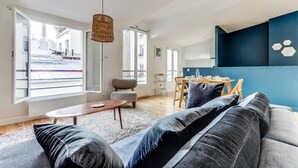 A modern living room with a sofa, a coffee table, and a dining area with chairs and a table. - The Sparkle - Tour Eifflel view by Mon Petit Faré (Paris)