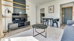 Una sala de estar moderna con un televisor de pantalla plana, una mesa de centro y una zona de comedor con una mesa y sillas.