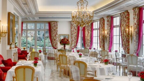 Un comedor formal con varias mesas, sillas y una araña.