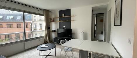 En modern lägenhet med ett matområde, en soffa, ett litet bord och en TV.
