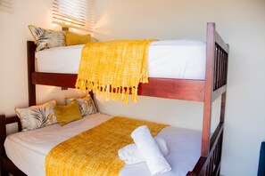 A bunk bed with a yellow blanket and pillows, a white towel, and a wooden headboard. - Villa Bahia Rincon: A Taste of Paradise (Samaná Province)