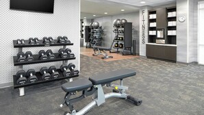 Una palestra con manubri, una panca e attrezzature per esercizi.
