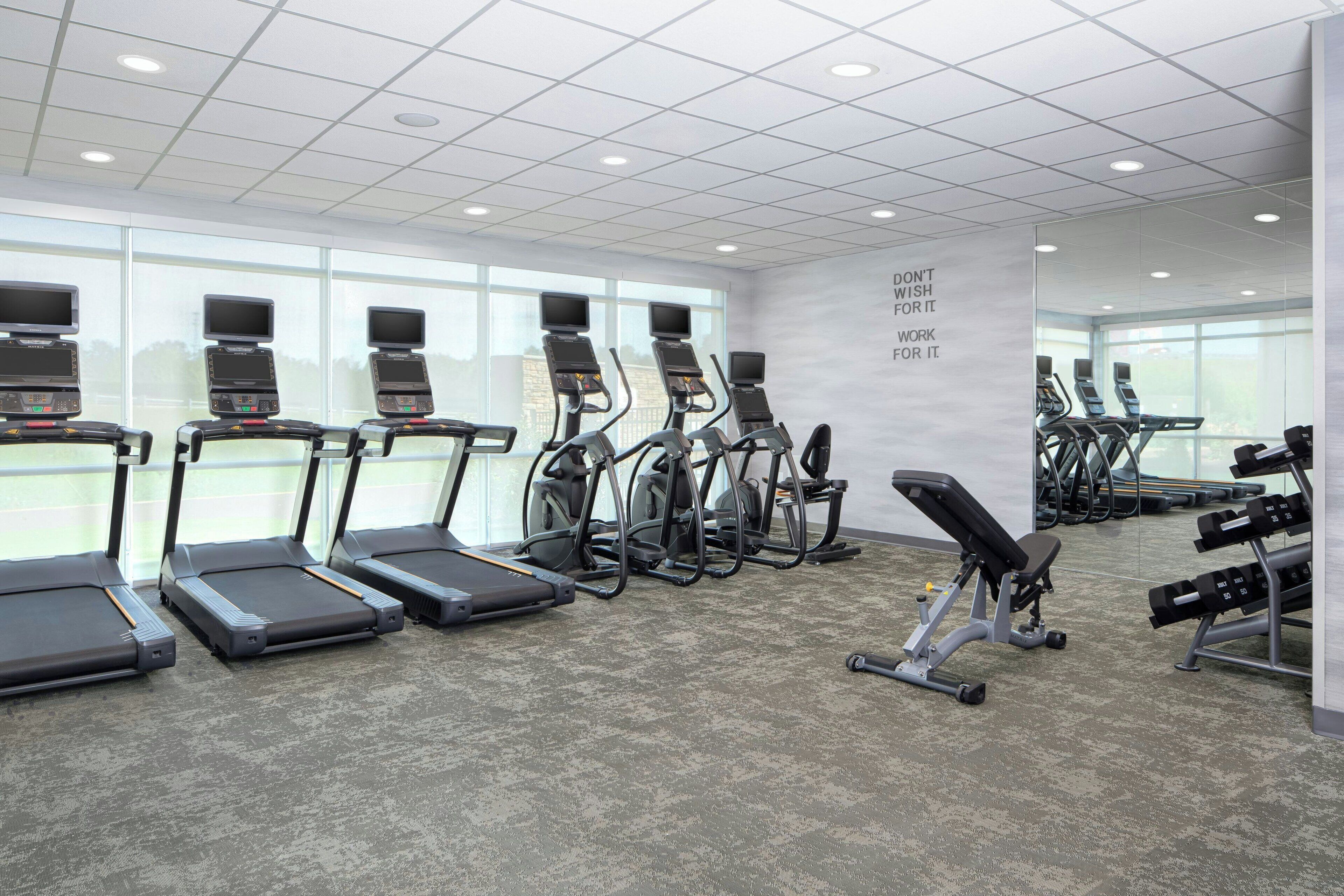 A gym with treadmills, elliptical machines, and weight benches.