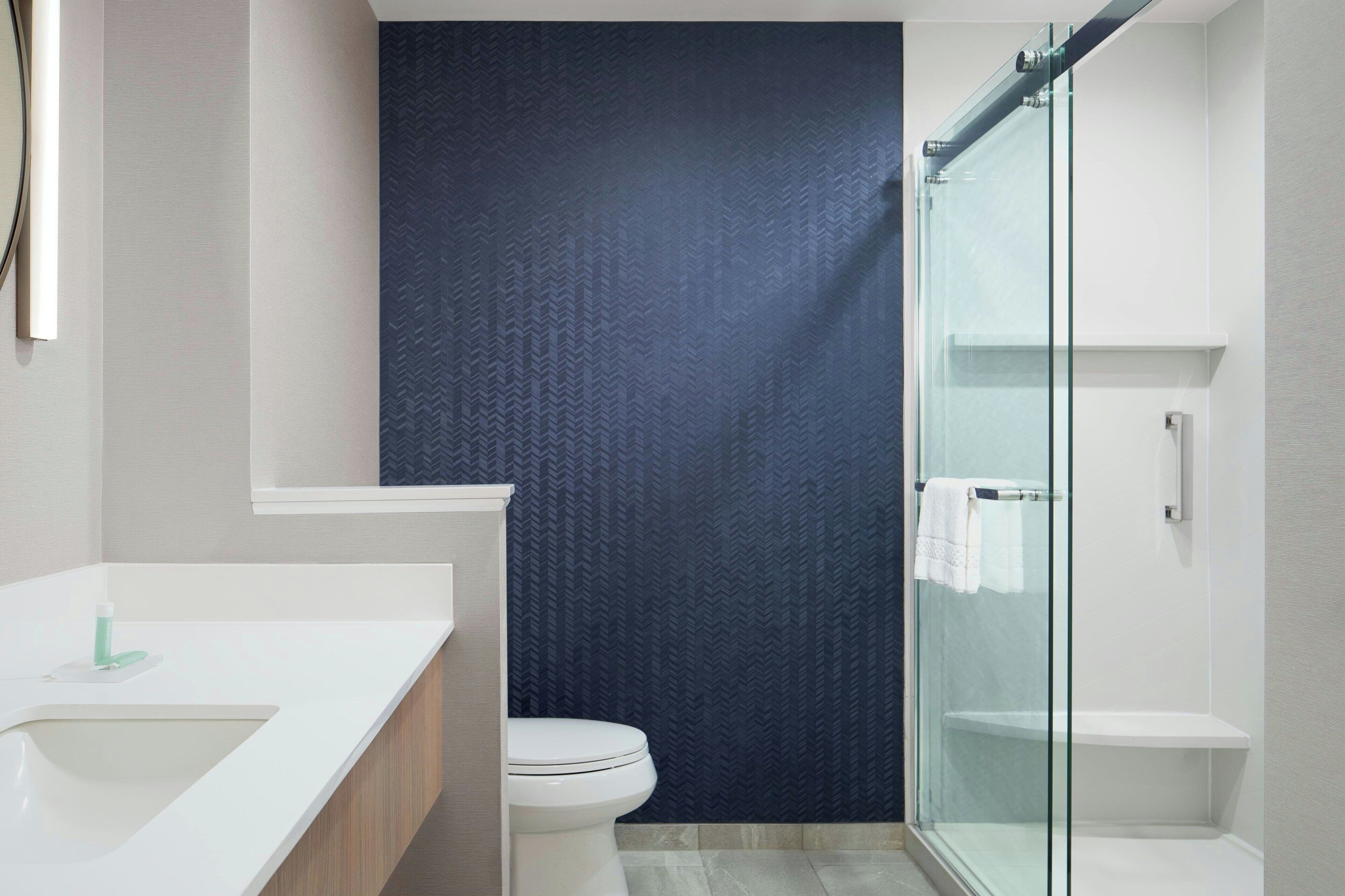 Une salle de bain moderne avec un lavabo blanc, des toilettes et une douche à parois de verre.