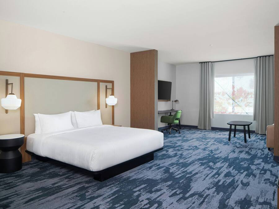 Habitación de hotel con una cama grande, un escritorio, una silla y un televisor.