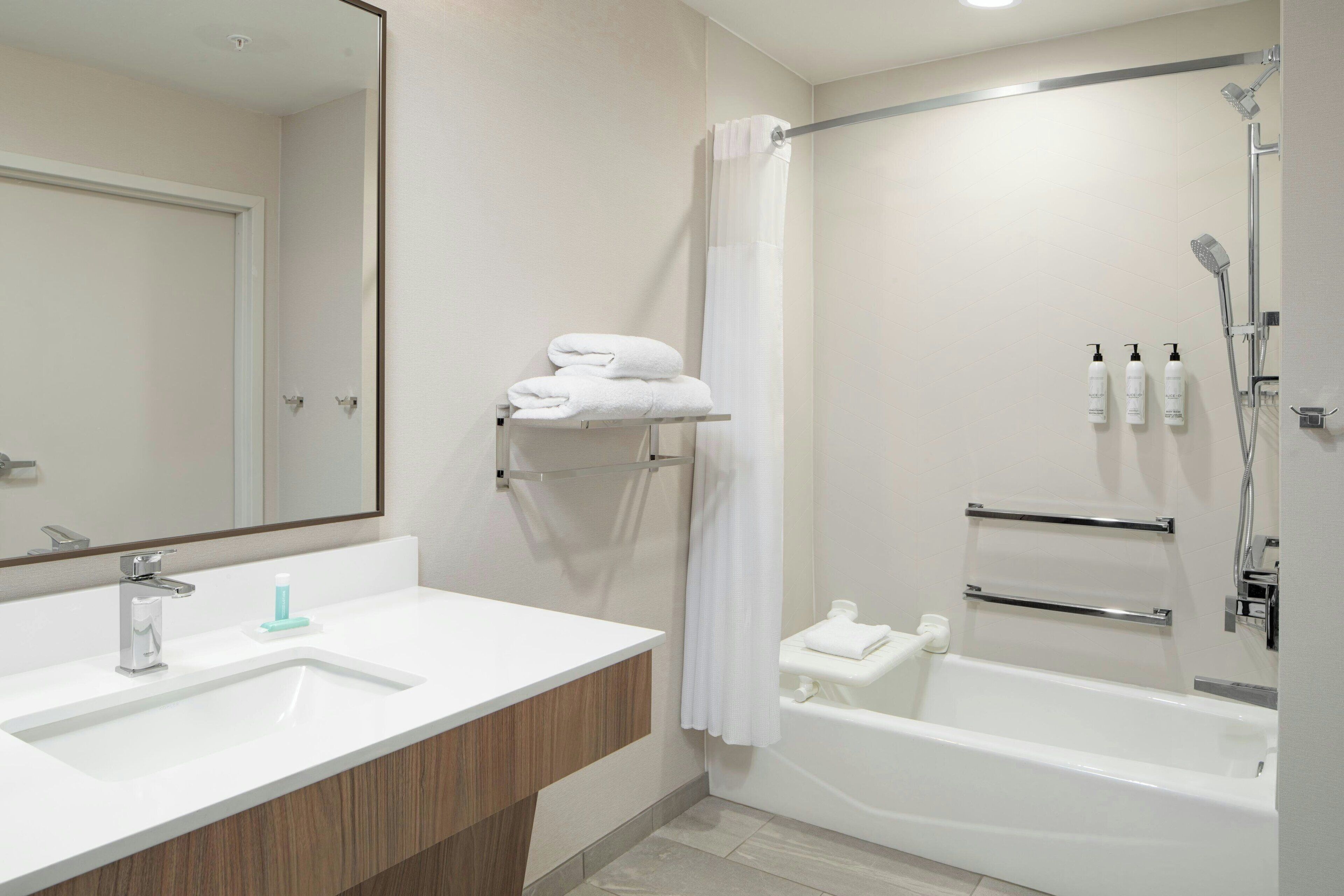 A modern bathroom with a white sink, mirror, and bathtub.