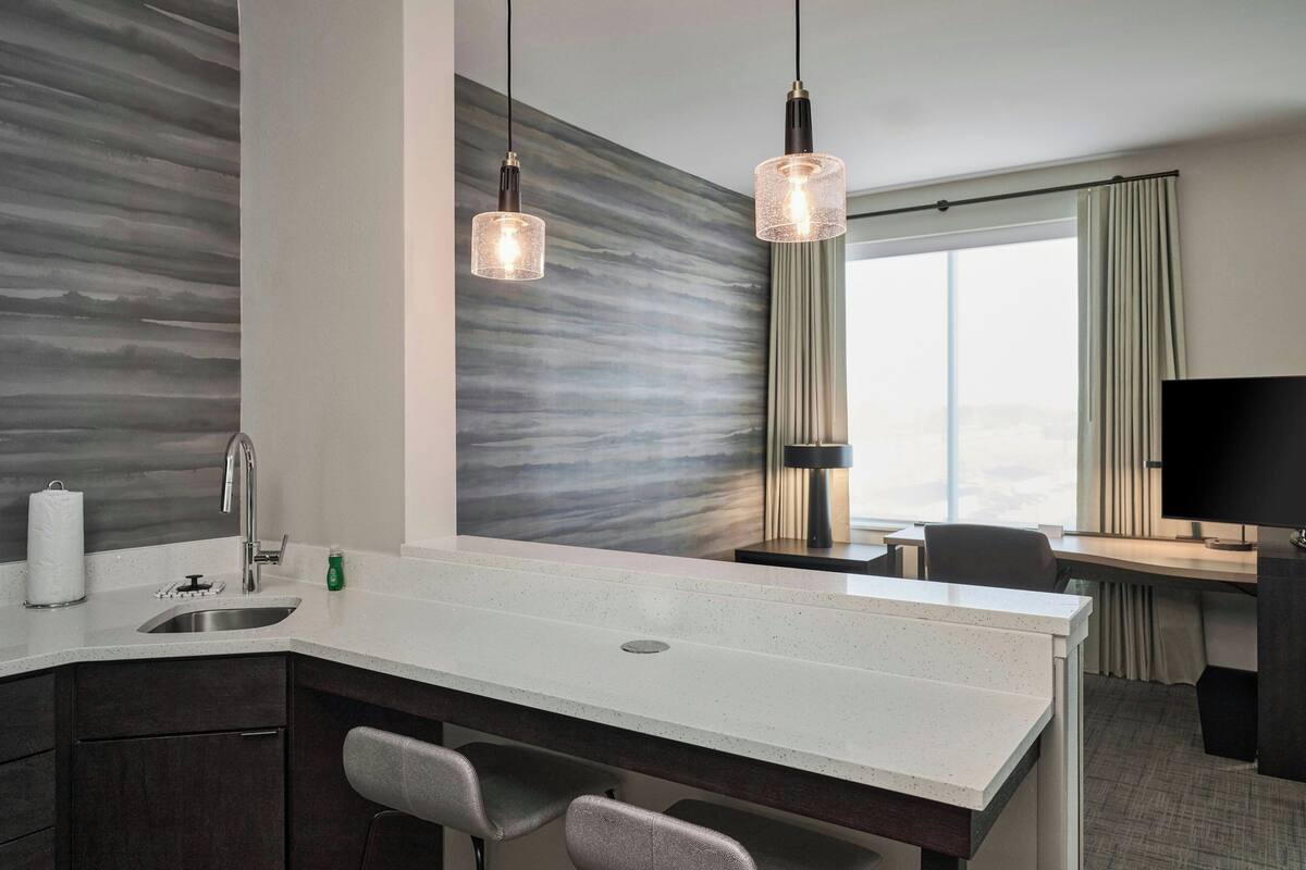 Una habitación de hotel moderna con cocina, una mesa de comedor y un televisor.