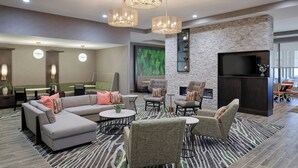 A modern hotel lobby with a sectional sofa, armchairs, a small round table, and a fireplace. - Residence Inn by Marriott Huntsville - Madison (Madison)