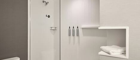 Une salle de bain moderne avec une douche à parois de verre, des toilettes et une étagère à serviettes.