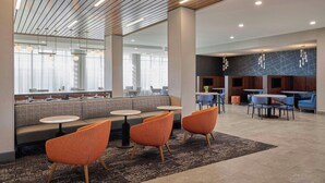 A modern hotel lobby with a seating area, a bar, and a dining area. - Courtyard by Marriott Huntsville-Madison (Madison)