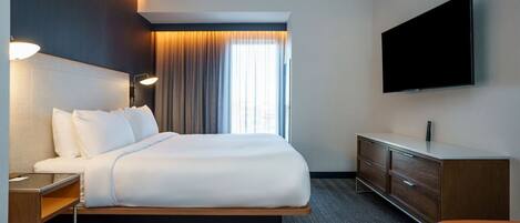 Une chambre d’hôtel moderne équipée d’un grand lit, d’un téléviseur à écran plat, d’un bureau et d’une commode.