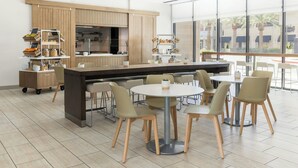 Un café moderne avec un îlot central, des tables rondes et des chaises.