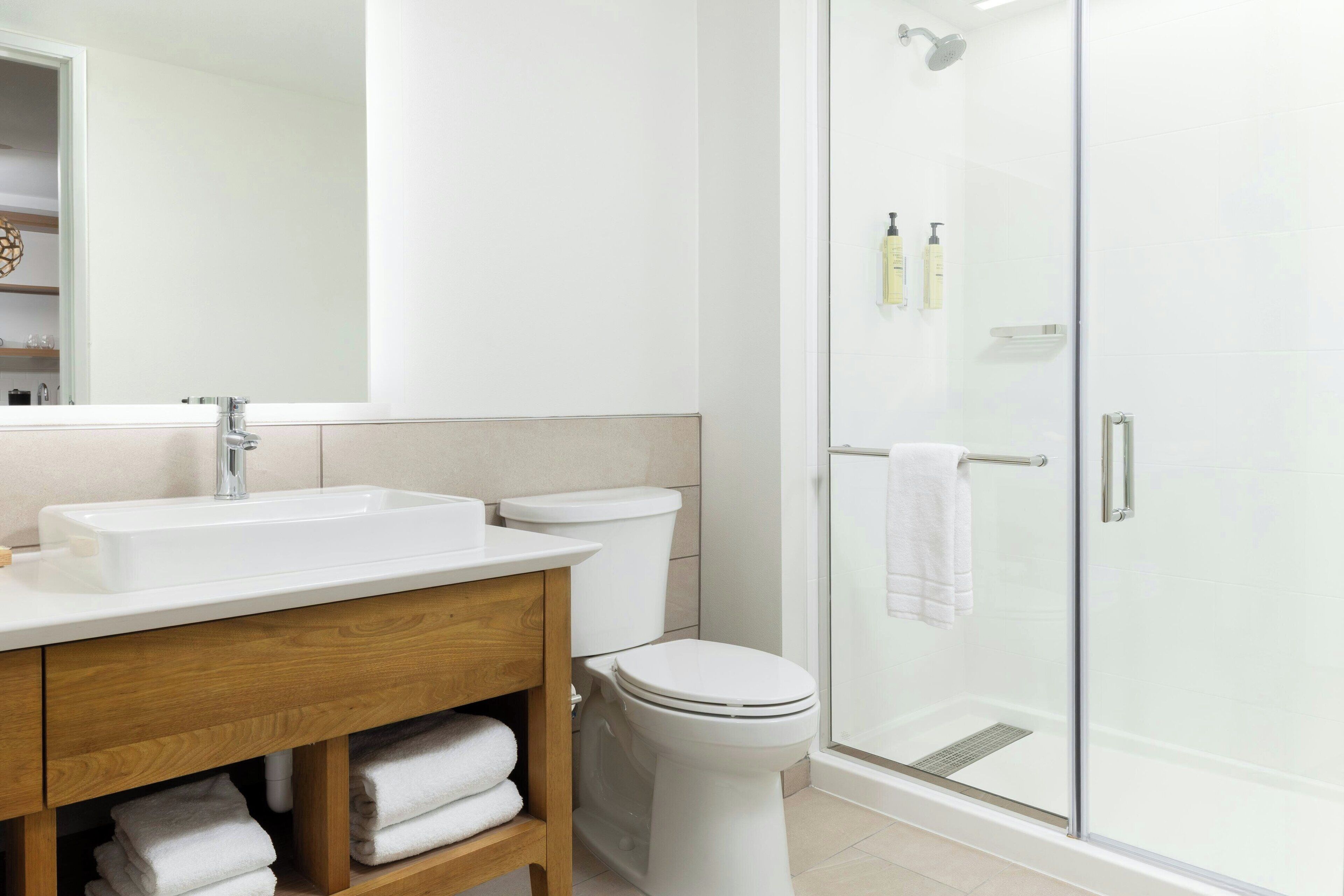 A modern bathroom with a white sink, toilet, and glass-enclosed shower.