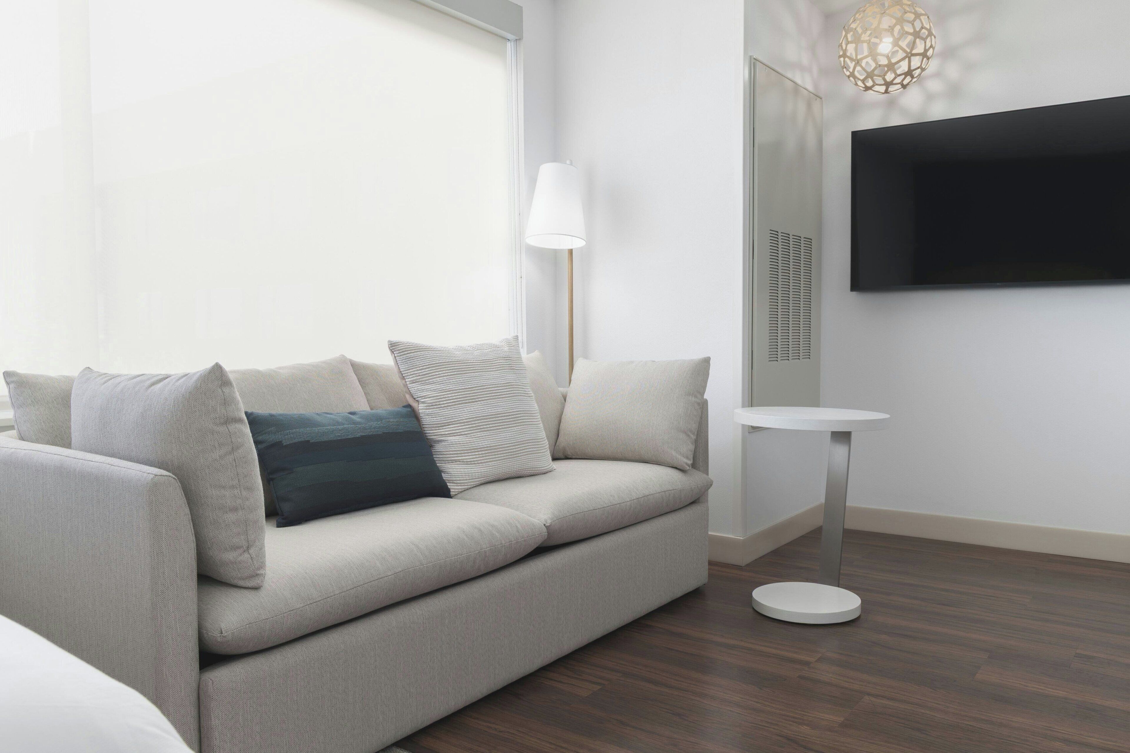 A modern living room with a sofa, a round side table, and a mounted TV.