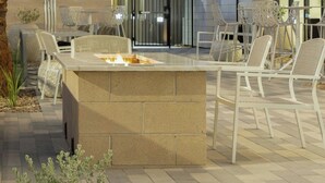 Un espace extérieur aménagé en patio, avec un foyer, des sièges, des guirlandes lumineuses et un parasol vert.