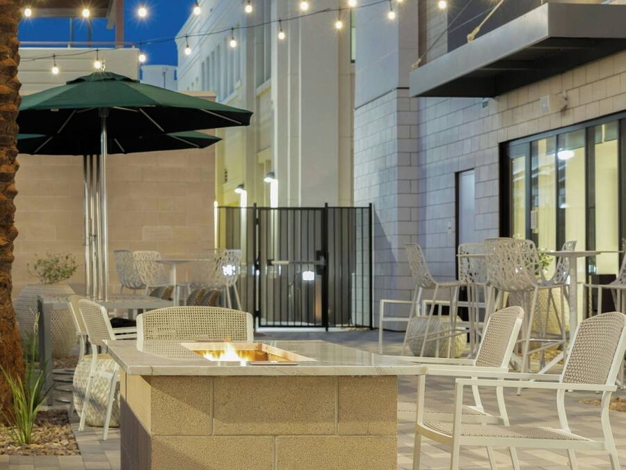 An outdoor patio area with a fire pit, seating, string lights, and a green umbrella.