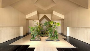 A spacious lobby with a modern geometric ceiling design, featuring two large planters with diverse greenery. - Fairfield By Marriott Suzhou Jinji Lake (Suzhou)
