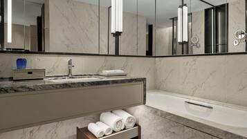 A modern bathroom with a marble sink, a large mirror, and a bathtub.
