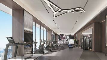 A modern gym with cardio equipment, weight machines, and a large window offering a city view.