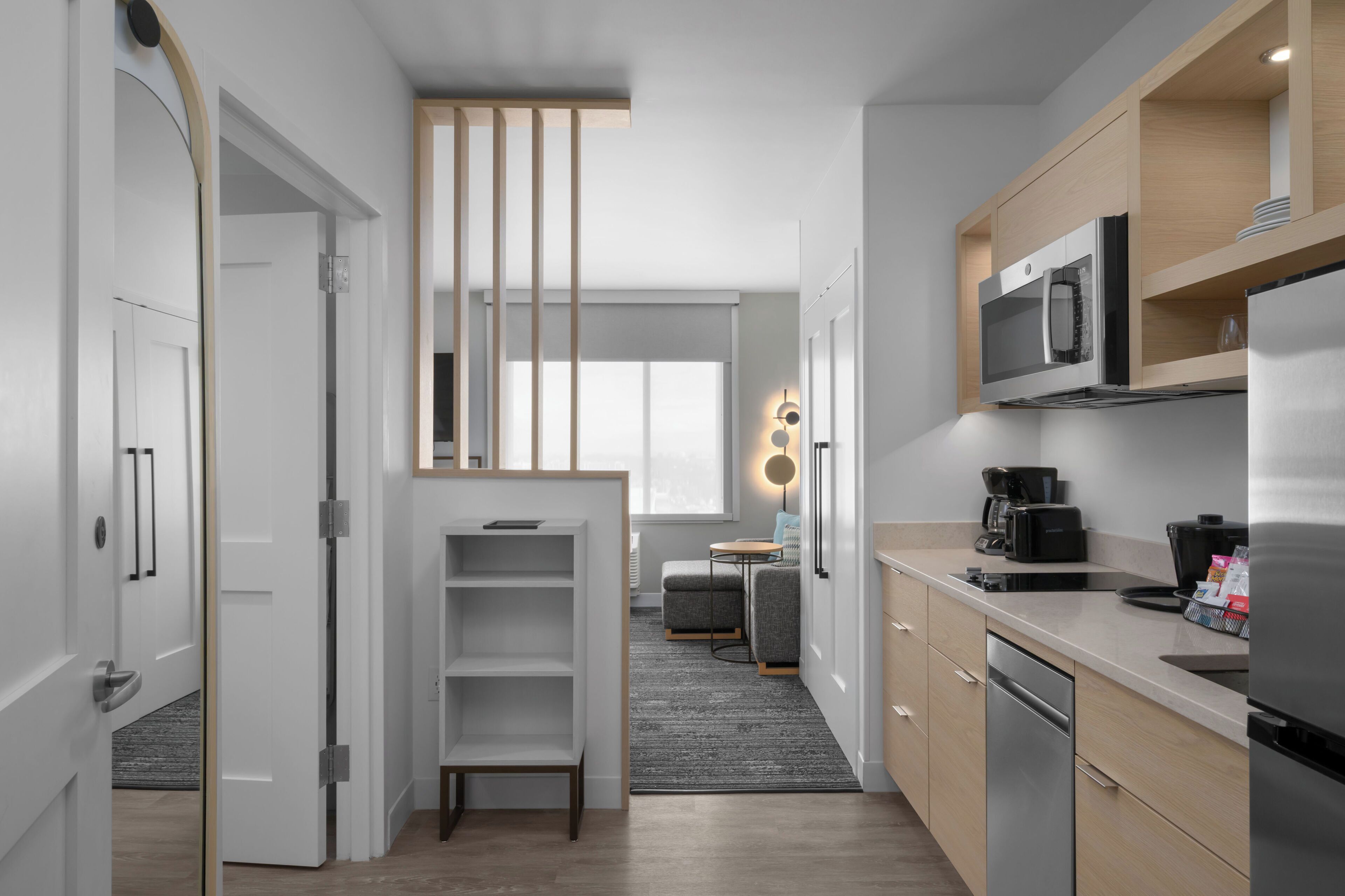Una cocina moderna con microondas, refrigerador y cafetera. Cuenta con un pequeño comedor con mesa y sillas.