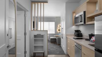 Una cocina moderna con microondas, refrigerador y cafetera. Cuenta con un pequeño comedor con mesa y sillas.