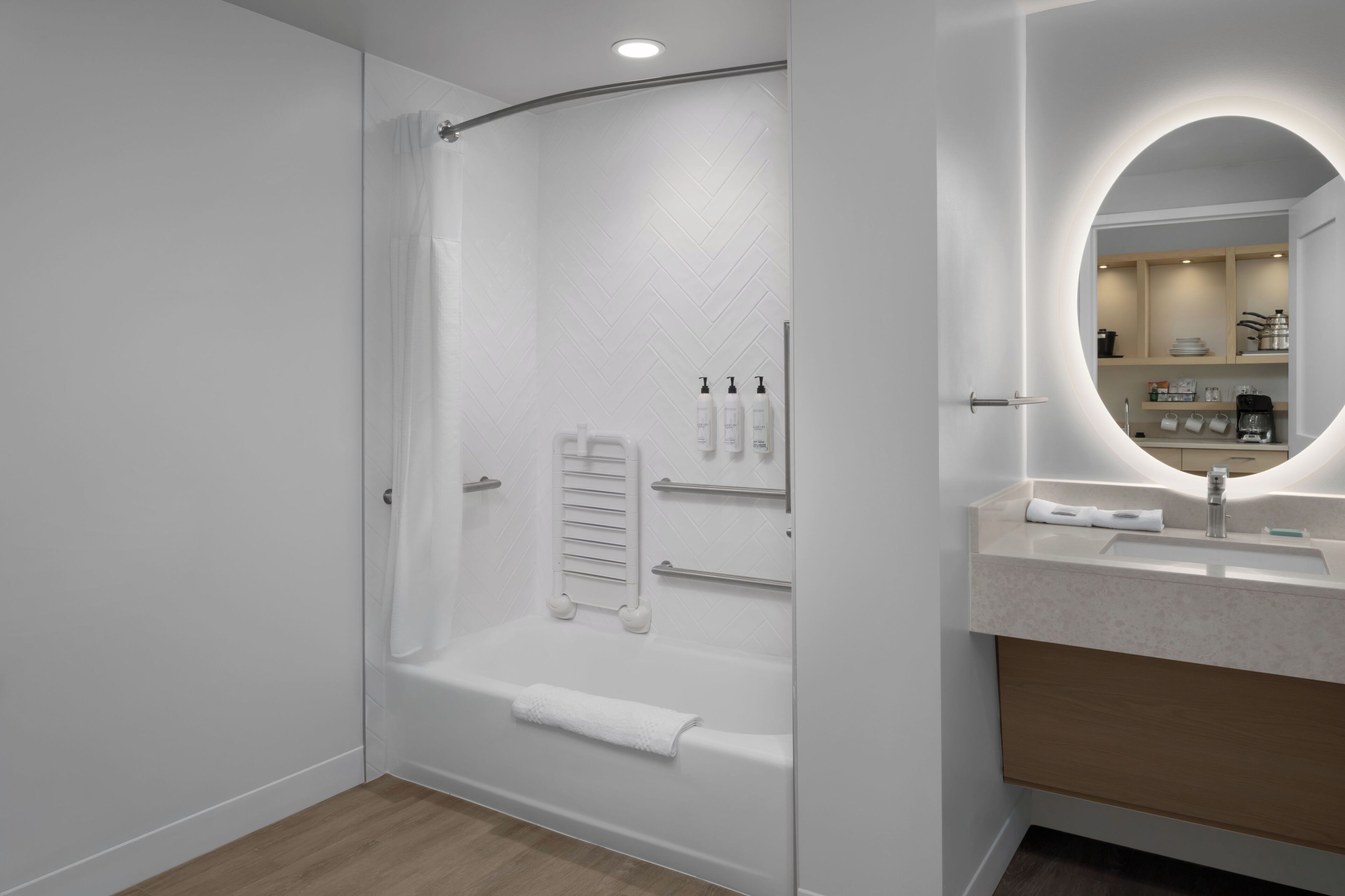 A modern bathroom with a glass-enclosed shower, a white vanity with a mirror, and a towel rack.