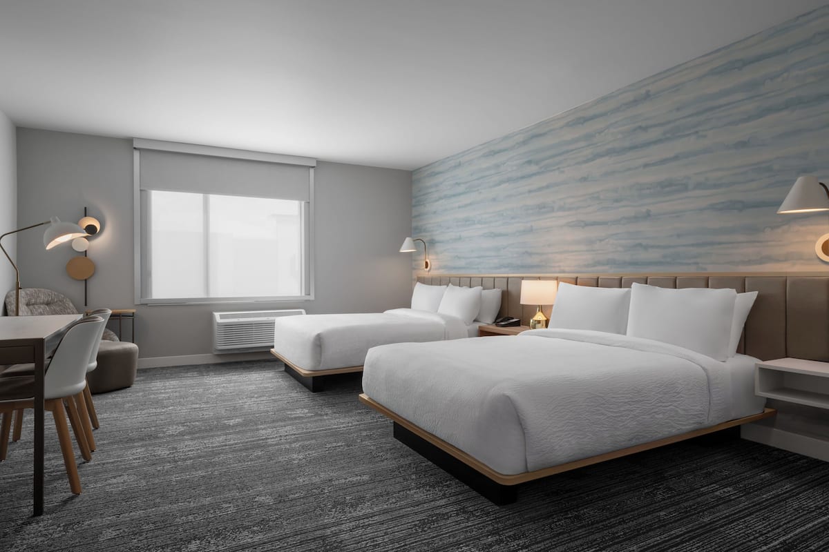 Une chambre d’hôtel avec deux lits, un bureau et une chaise.