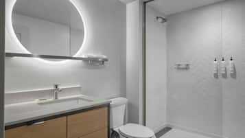 Un baño moderno con un espejo redondo, un inodoro, un lavamanos y una zona de ducha.