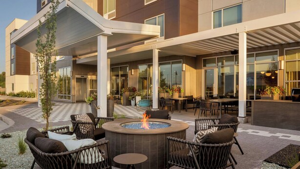 A modern outdoor seating area with wicker furniture, a central fire feature, and a covered patio. - Towneplace Suites By Marriott Nampa (Nampa)