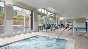 An indoor swimming pool with a hot tub, lounge chairs, and large windows offering views of the outside. - Towneplace Suites By Marriott Nampa (Nampa)