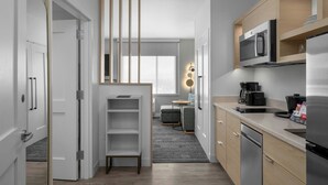 A modern kitchen with built-in appliances, a dining area with a table and chairs, and a view through a window. - Towneplace Suites By Marriott Nampa (Nampa)