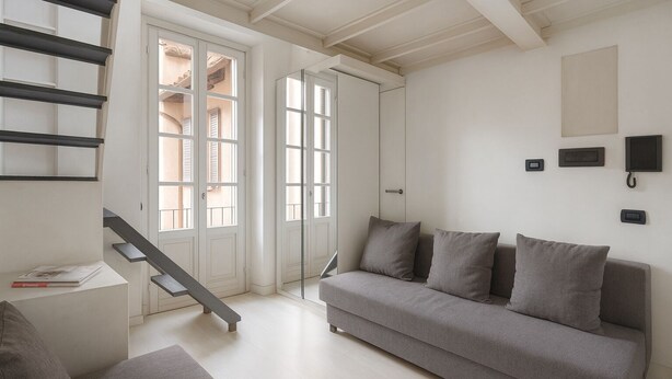 Ein modernes Wohnzimmer mit einem grauen Sofa, einer Bank und einer Treppe mit weißen Türen.