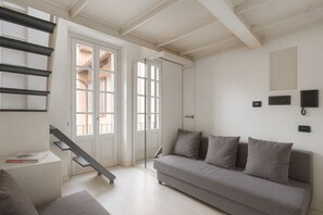 A modern living room with a grey sofa, a bench, and a staircase with white doors. - Casa Milano - Urban Studio Chic (Milan)