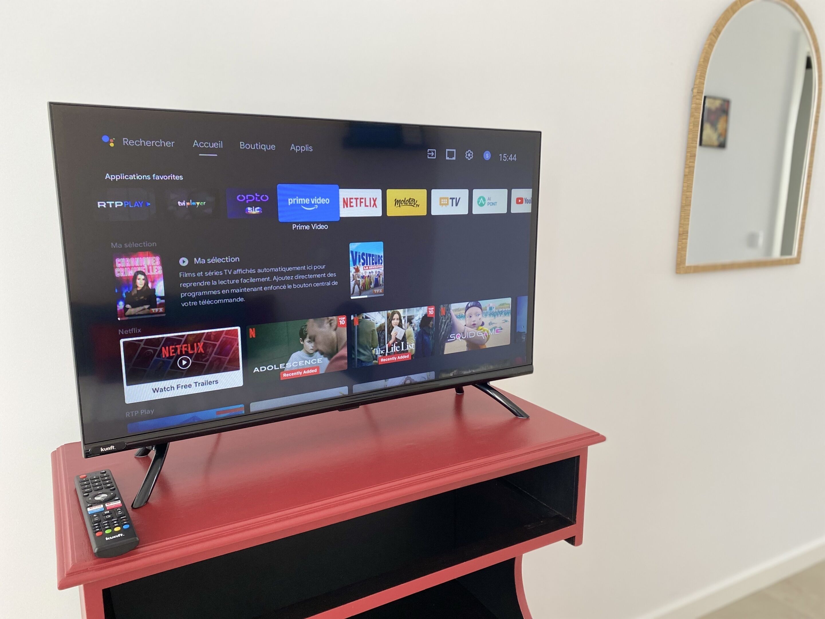 A flat-screen TV on a red stand displaying a streaming service interface with various apps and content.