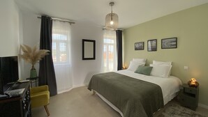 Una camera da letto con un letto, una scrivania, una sedia, una lampada e una finestra con tende.