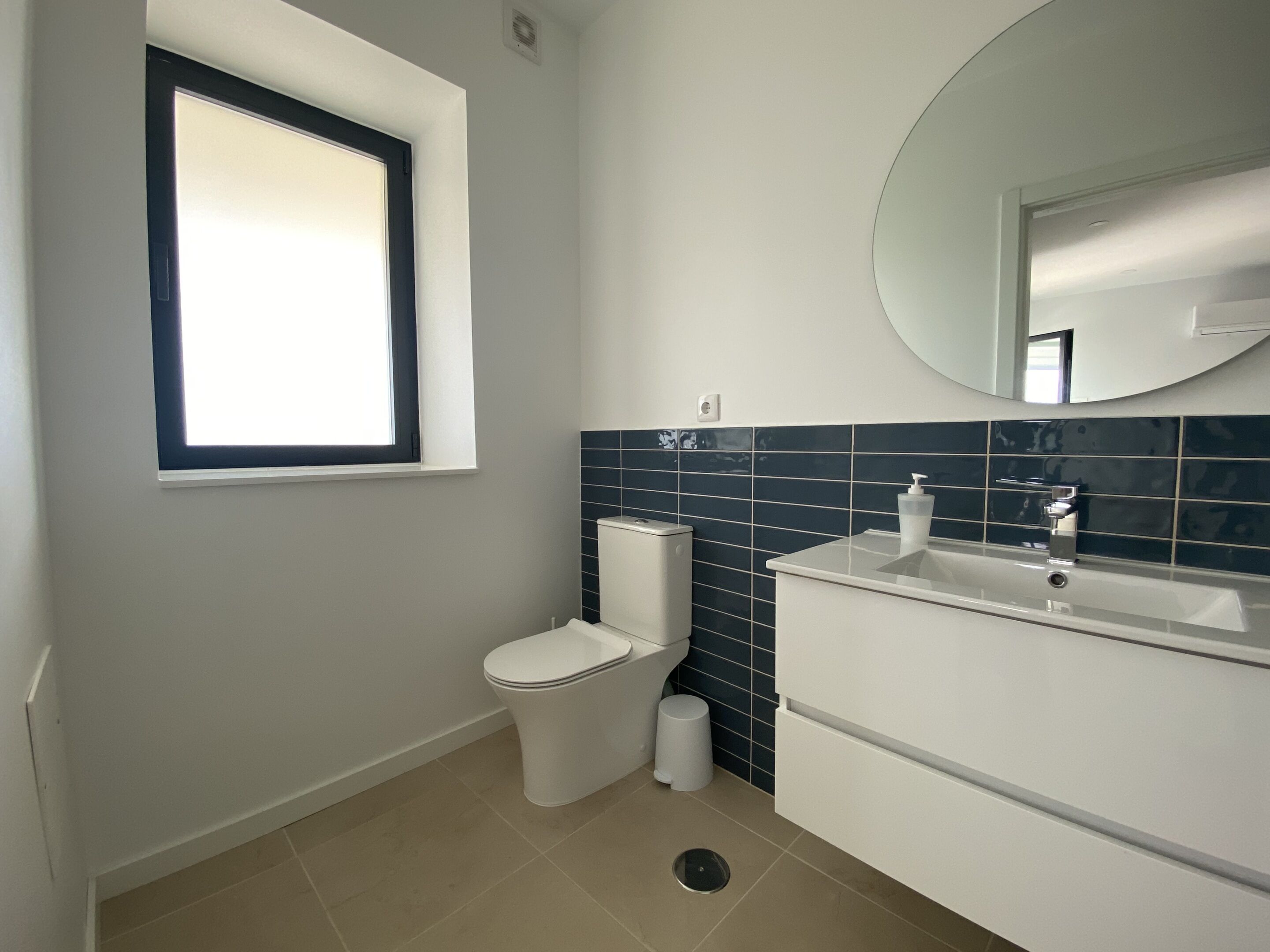 Un baño con inodoro, lavamanos y ventana.