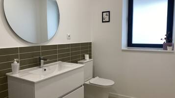 Un baño con un lavamanos blanco, inodoro y ventana con vistas.