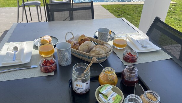 Tavolo imbandito per la colazione all'aperto, con pane, frutta e salse.