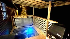 Ein Außenbereich mit Whirlpool, einer Holzterrasse, einem Grill und einer überdachten Lounge-Ecke.
