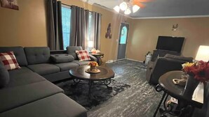 Ein Wohnzimmer mit Ecksofa, Couchtisch, Fernseher und Kamin.